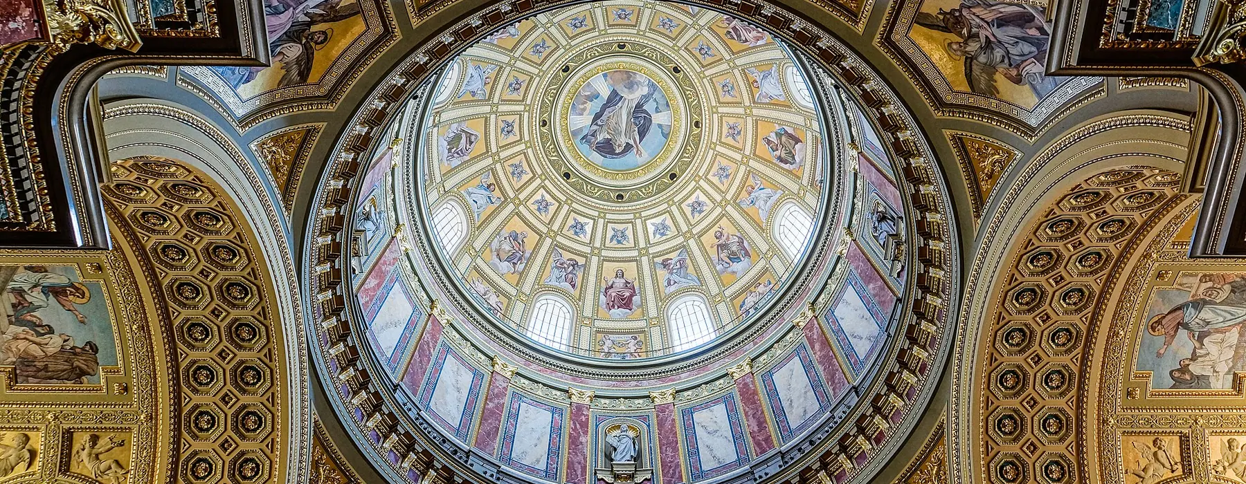 The central dome of St Stephen's Basilica seen from below, with a ring of windows, mosaic panels and gilded coffering